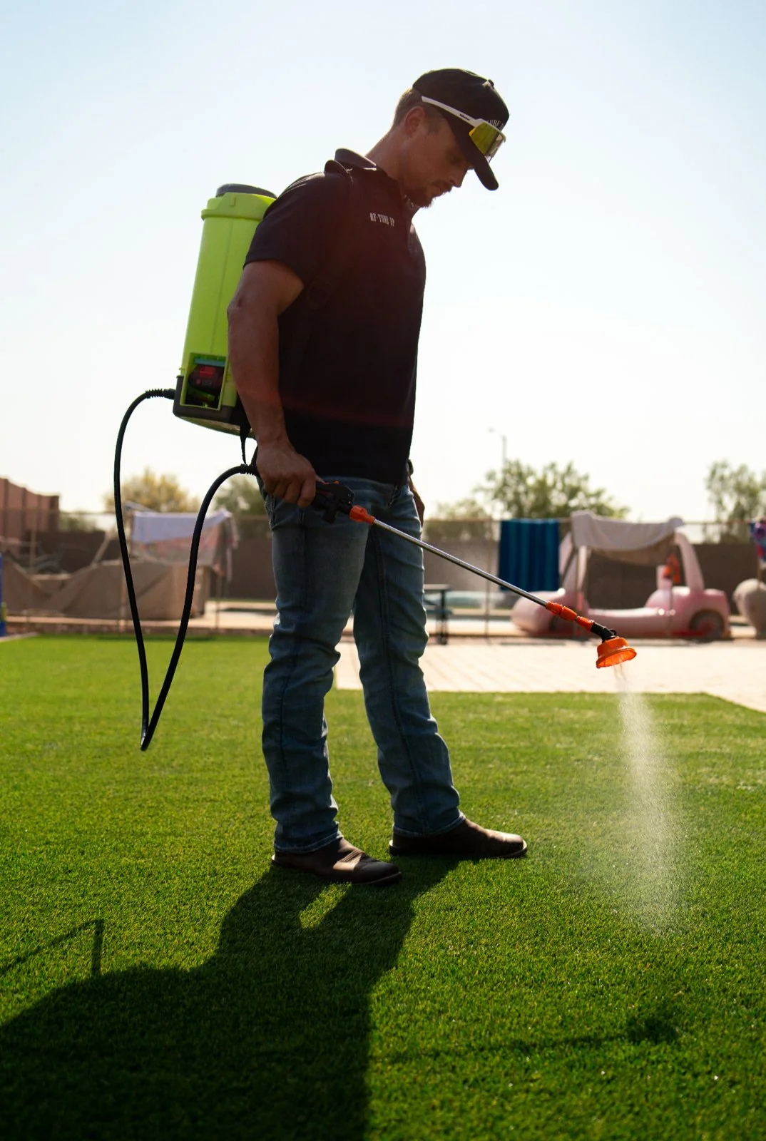 Chase Adams applying pet-safe turf treatment in a Mesa backyard