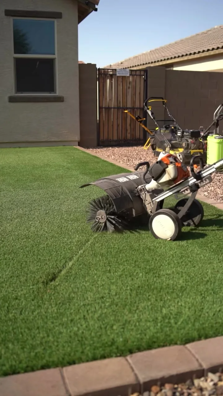 Technician power brooming artificial turf in a Mesa backyard